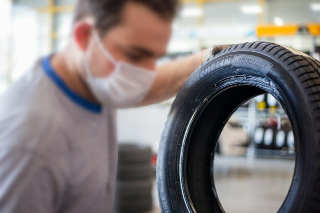 Technician with a stack of winter tires in a tire shop