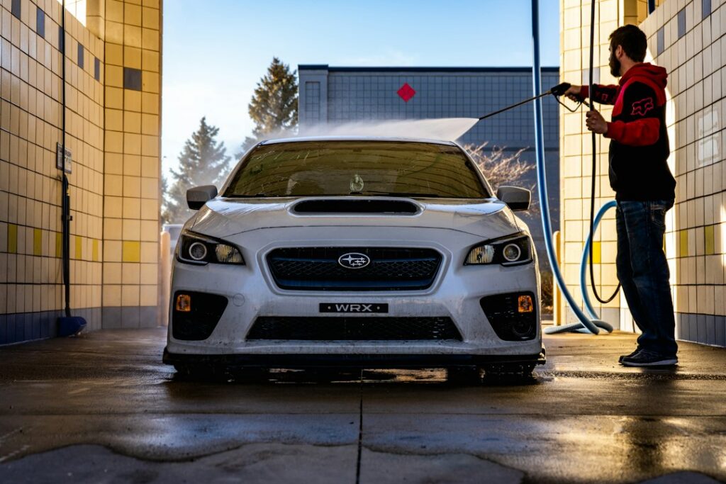 Car wash owner standing by a tunnel exit with a clean car