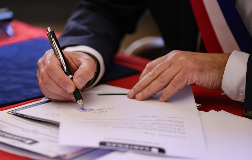 Close-up of a business contract being signed across a desk