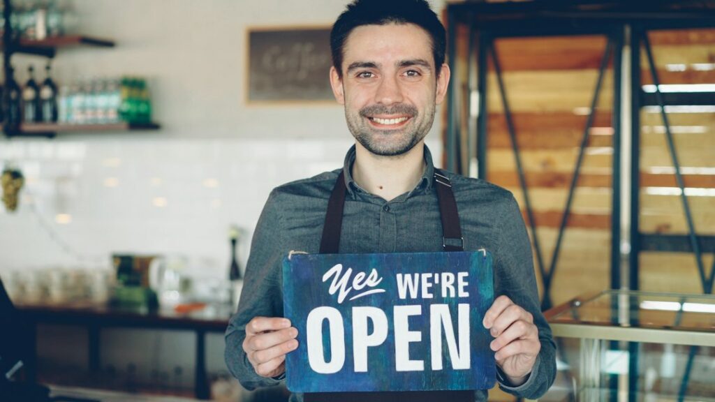 Small business owner flipping the open sign after reopening the shop